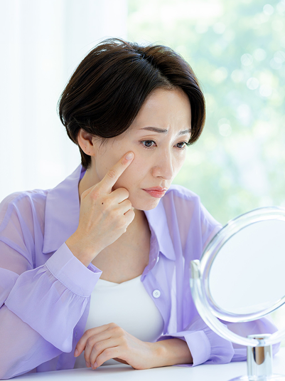 鏡で目もとを気にする女性のイメージ写真